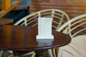 pequeño cuadrado de madera tablero ,allá es espacio para escritura o adjuntando mesa números, adjunto a el menú, adjunto a el qr código para pago, mira elegante, compacto, adecuado para restaurantes, café tiendas foto