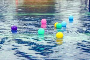 Colorful plastic balls move up and down in the same place on the surface of the water as surface waves, which are transverse waves, pass by. photo