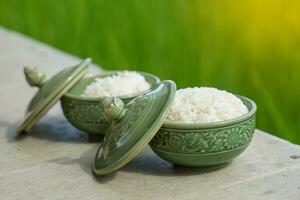 Bowl of steamed rice on green rice field background It is an important staple food for Asian people that must be eaten at every meal with other side dishes. Soft and selective focus. photo