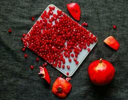 Ripe pomegranate seeds on a plate on a black background photo
