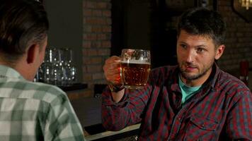 Mature bearded man talking to his friend while drinking beer at the pub video