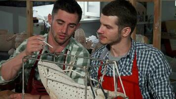 Two male sculptors decorating statue at their workshop video