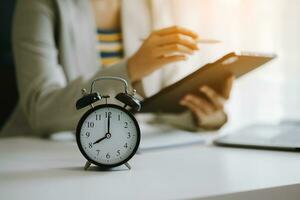 Alarm clock on the desk. Business hand using smartphone, laptop and tablet  working in modern office building or home photo