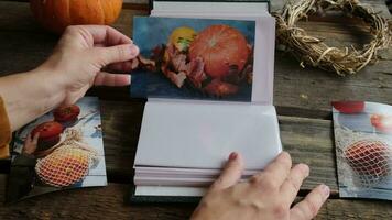Photo printing. Hands put autumn printed photos in picture album. video