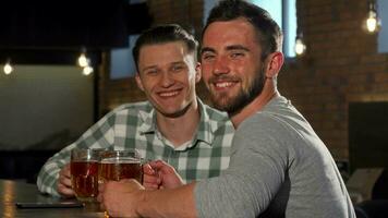 Cheerful men smiling to the camera, while having beers at the bar video