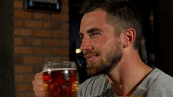 Happy man smiling to the camera holding up his beer video