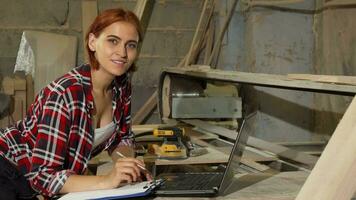 bellissima femmina falegname sorridente per il telecamera a sua laboratorio video