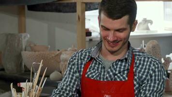 Handsome cheerful male potter enjoying working at his studio video