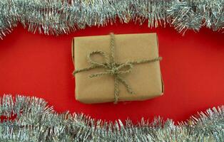 New Year's postcard. Gift and tinsel on a red background. photo