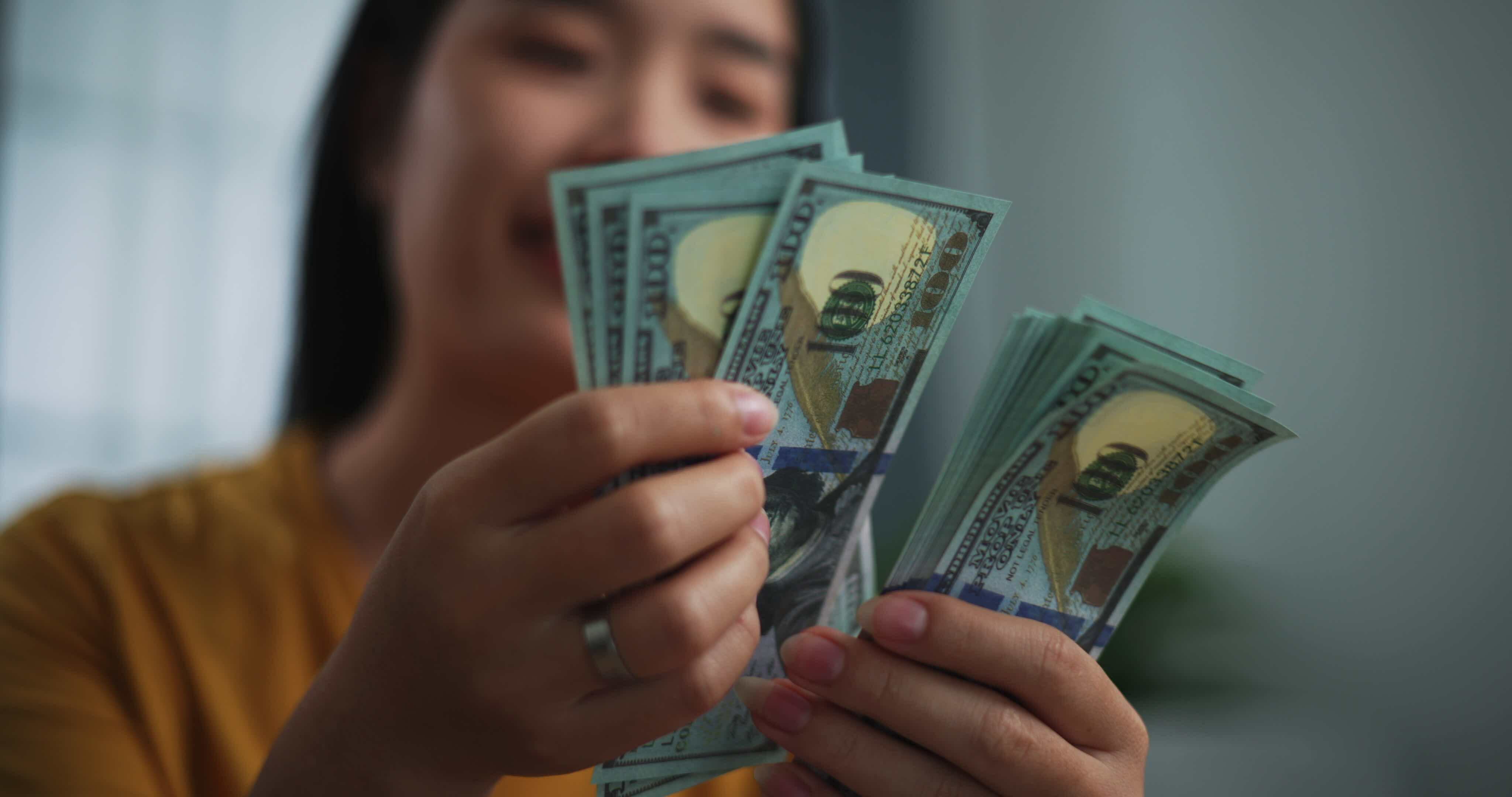 Footage of young Asian woman enjoy counting cash dollars banknotes on
