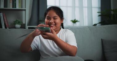 Footage of young Asian woman enjoy counting cash dollars banknotes on sofa in the living room at home. video