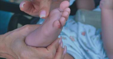 bebé en un paseante con desnudo pies. manual masaje de un del bebe pie en un paseante video