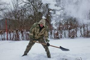 hombre borra el yarda de nieve con pala. pesado nevada en invierno. alto nivel de nieve. Nevado ventisquero. foto