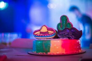 Birthday cake decorated in the style of Mexico. Cake at the party. Cake with gingerbread cookies in the form of sambrero and cactus. photo