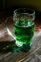 glass of beer at a party where they celebrate St. Patrick's Day. Brewed booze for an outdated Patrick's. Mug with green alcohol in a pub on a vintage wooden table. photo