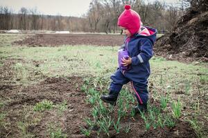 child tramples bed with onions in garden. Destruction of the crop. Harm to plants. photo
