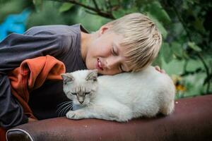 boy put head on back of cat. Friendship between child and pet. Animal care. photo