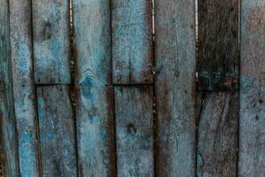 The old fence with wooden planks with torn blue paint photo