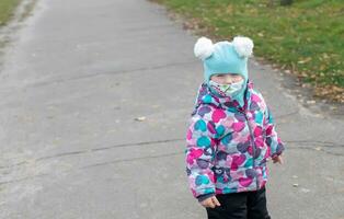 Little girl in winter overalls surgical bandage. Coronavirus, illness, infection, quarantine, medical mask, COVID-19. Boy in a medical mask. Quarantine and protection virus, flu, epidemic COVID-19. Coronavirus quarantine. photo