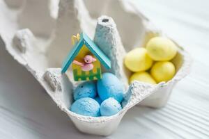 un manojo de amarillo y azul huevos en huevo caja de cartón. cerca el casa con un pájaro. el concepto de un abandonado hogar de Ucrania para el Pascua de Resurrección día festivo. foto