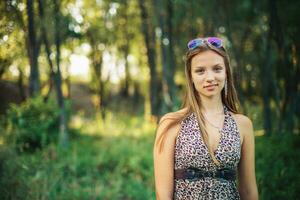 Beautiful girl in a light sarafan with developing hair on forest background. Girl is smiling standing. photo