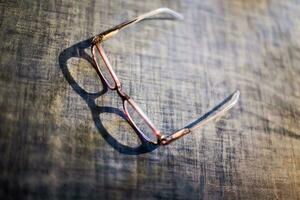 lentes acostado en el cocina mesa. el sombra de el lentes en el mesa. antiguo de los hombres lentes. suave enfocar. película grano. blured desenfocado foto