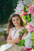 a little girl in a pink dress standing in front of a floral wreath photo