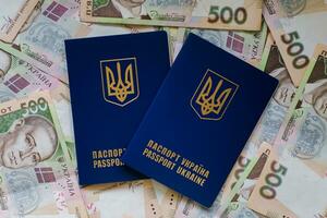 Two international passport of Ukrainians lie on pile of money from five hundred-pound banknotes. Passports for departure to Europe without visas. Visa-free regime for Ukraine. photo