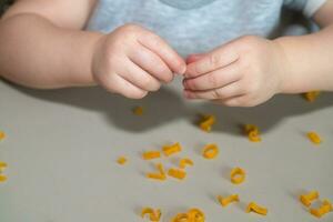 mano de niño coleccionar letras desde pasta desde mesa. desarrollo de multa motor habilidades de manos. montessori técnica. aprender letras y alfabeto en juego foto