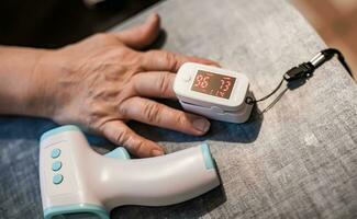 Devices for self-gnoging in coronavirus. Infrared thermometer and Pulse Oximeter, finger digital device to measure person's oxygen saturation. photo