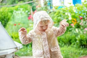 un pequeño niña es teniendo divertido en el verano lluvia. camina en el Fresco aire en el verano en ninguna clima con niños foto