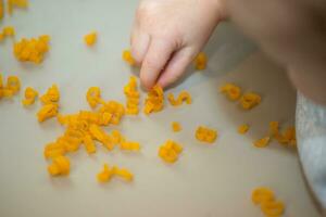 hand of child collecting letters from pasta from table. development of fine motor skills of hands. Montessori technique. Learn letters and alphabet in game photo