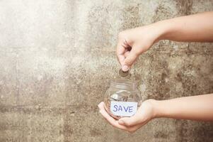 save money concept with hand holding jar with save written on it photo