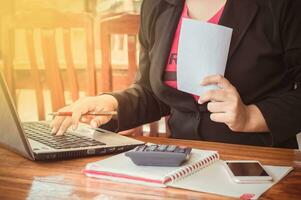 Close up of business woman's hand writing on a notebook and holding a white paper photo