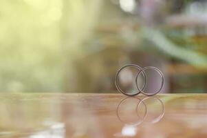 two wedding rings on a table in front of a blurred background photo