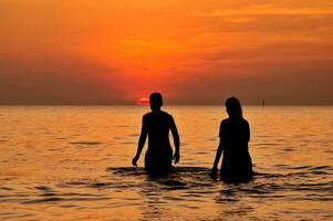 silueta de Pareja a el mar a puesta de sol foto