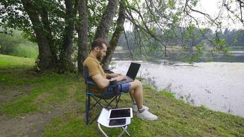 trabajando con computadora por el lago. video