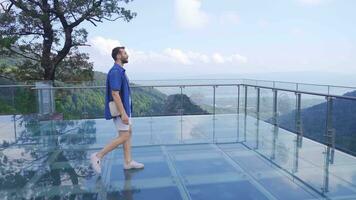 The man walking in the valley watches the valley from the glass terrace. video