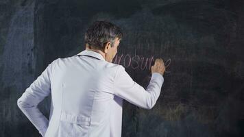 Male doctor writing Neurosurgery on the blackboard. video