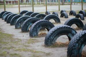 Wheels dug into the ground at school stadium. Arrangement of children's playgrounds. photo