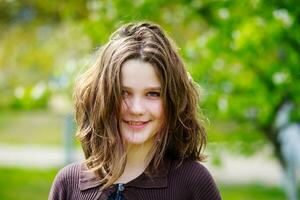 hermosa niña entre Cereza flores en primavera. retrato de un niña con marrón pelo y verde ojos. foto