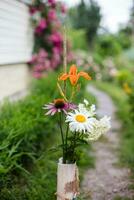 Bouquet of summer flowers in a vase standing on a footpath near the house photo