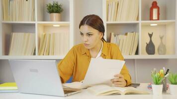 kvinna studerande arbetssätt mellan papper och bärbar dator. video