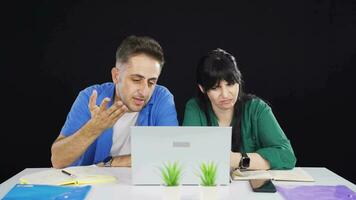 The couple reacting negatively to what they see on the laptop. video