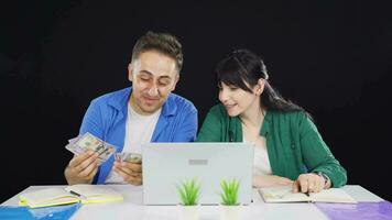 casal contando dinheiro enquanto olhando às computador portátil. video