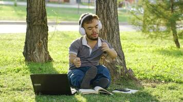 al aire libre Universidad enano estudiante escuchando a música y contento. video