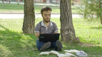 un Universidad enano estudiante haciendo su deberes al aire libre es fracasado y infeliz. video