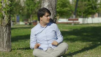 Young man sitting on the ground outdoors with fear. video