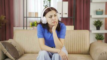 Young woman listening to music with headphones is unhappy and sad. video