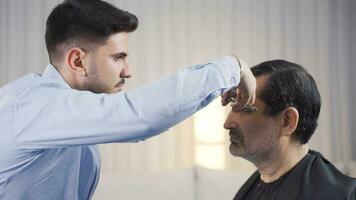 The man in need of care is getting his hair cut in his home. video